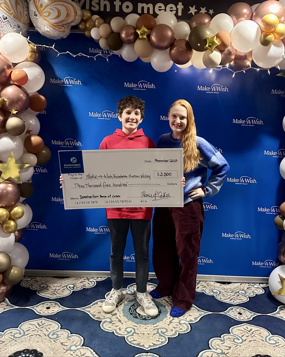 Two young PeaceofCakes supporters presenting a $3,500 donation check to Make-A-Wish Foundation Hudson Valley in November 2024