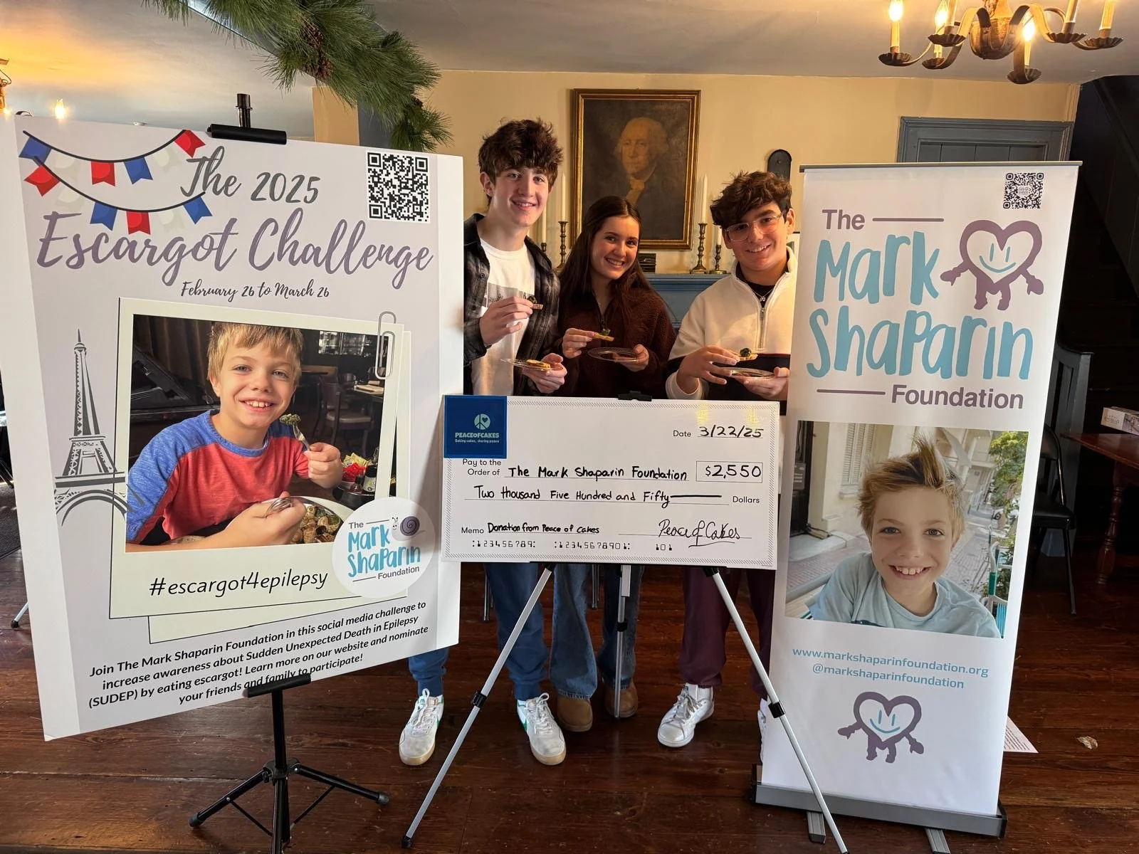 Three PeaceofCakes supporters presenting a $2,550 donation check to The Mark Shaparin Foundation in March 2025
